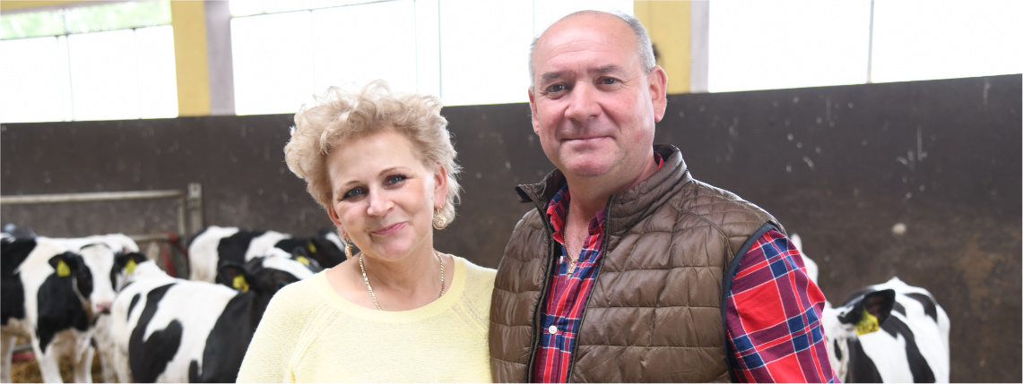 Teresa i Mariusz Smolarkowie, zwycięzcy AgroLigi 2021 W oborze przy boksie z krowami stoi kobieta i mężczyzna, którzy obejmują się i uśmiechają. Za nimi są krowy.