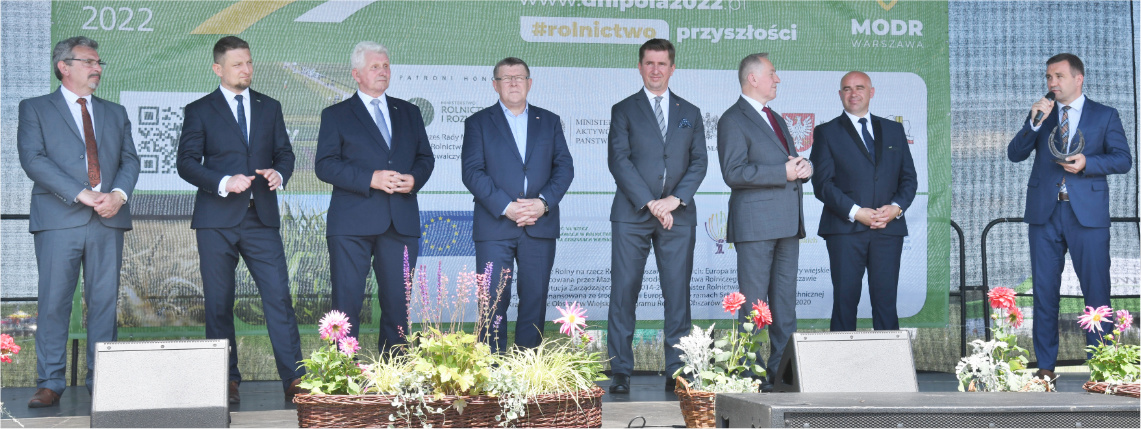 4. Krajowe Dni Pola odbędą się w Sielinku w dniach 1-5 czerwca 2023 Na scenie w rzędzie stoi kilku mężczyzn w garniturach. Jeden z nich przemawia.