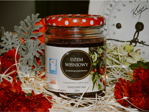 Domowe przetwory owocowe to kulinarny atut tego miejsca Na stole wśród ozdób stoi słoik z dżemem wiśniowym domowej produkcji.