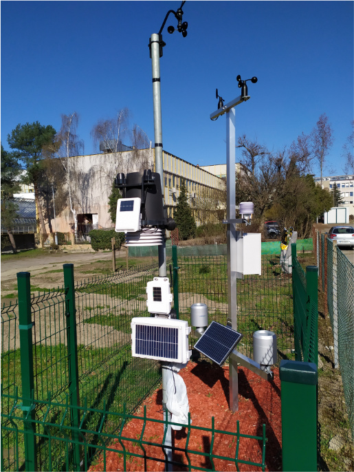 Konstrukcja z urządzeniami pomiarowymi stacji meteorologicznej. Stoi na ogrodzonym kawałku podłoża.