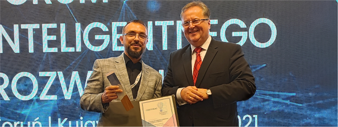 Maciej Zacharczuk, kierownik projektu eDWIN, odebrał Polską Nagrodę Inteligentnego Rozwoju, którą otrzymał Wielkopolski Ośrodek Doradztwa Rolniczego w Poznaniu Maciej Zacharczuk (po lewej) stoi obok mężczyzny w średnim wieku i trzyma nagrodę z dyplomem. Na niebieskim tle z tyłu jest napis "Forum Inteligentnego Rozwoju".