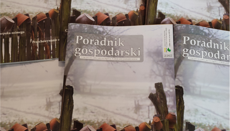 Na stole leżą lutowe numery Poradnika Gospodarskiego. Na okładce jest napis "Poradnik Gospodarski" oraz zdjęcie ukazujące gliniane garnki na drewnianym płocie.