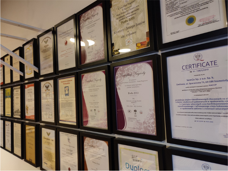 Wnętrze pomieszczenia. Na ścianie wiszą różnorodne certyfikaty i dyplomy dla firmy Semco.