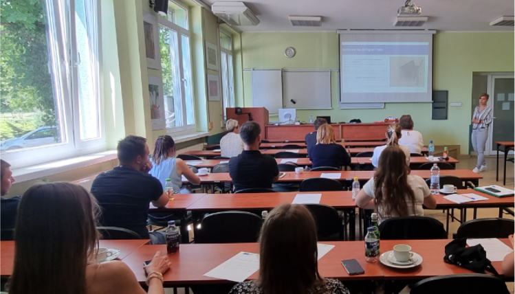 Drugie spotkanie z cyklu szkoleń dotyczących żywienia krów mlecznych Sala lekcyjna. W ławkach siedzą słuchacze, widoczni od tyłu. Przed nimi jest wykładowca, który omawia prezentację wyświetloną z rzutnika na ekranie.