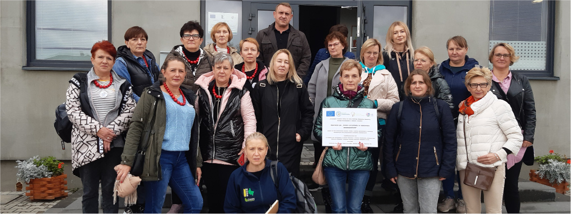 Sprawozdanie z wyjazdu studyjnego pod nazwą „Dobre przykłady w rolnictwie ekologicznym” Przed wejściem do budynku stoi grupa osób, która pozuje do zdjęcia.
