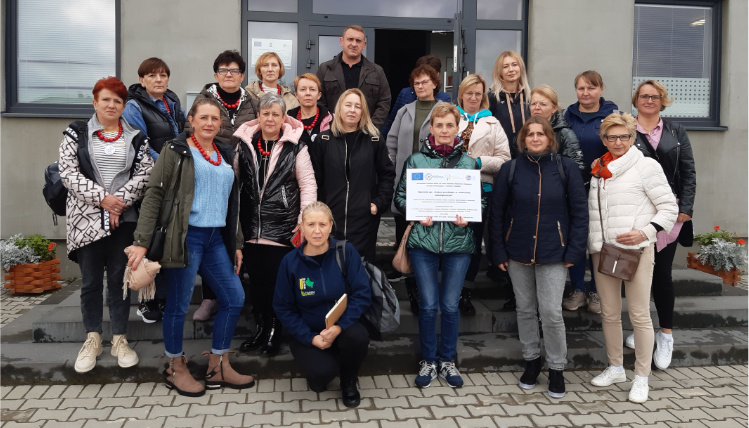 Sprawozdanie z wyjazdu studyjnego pod nazwą „Dobre przykłady w rolnictwie ekologicznym” Przed wejściem do budynku stoi grupa osób, która pozuje do zdjęcia.