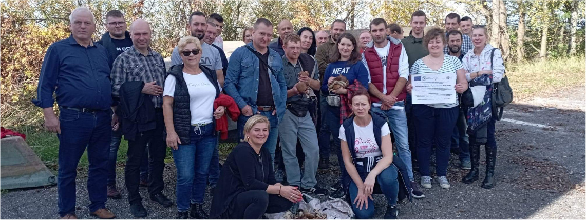 Grupa osób w lesie pozuje do zdjęcia i uśmiecha się.