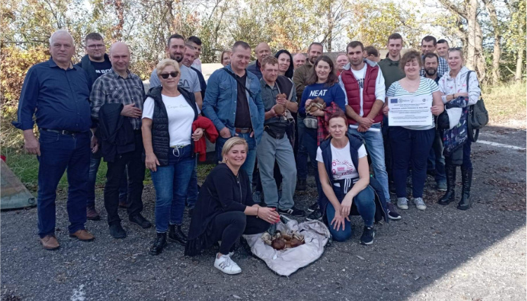 Grupa osób w lesie pozuje do zdjęcia i uśmiecha się.