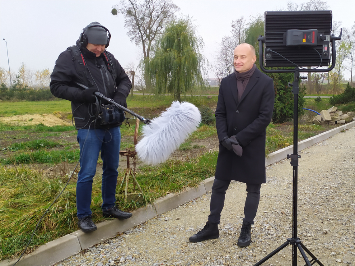 Doradca WODR wypowiada się do mikrofonu trzymanego przez mężczyznę w średnim wieku. Przed nimi stoi lampa.