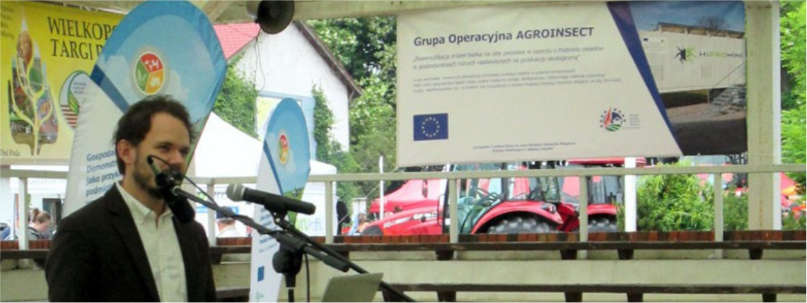 Wielkopolskie Targi Rolnicze w Sielinku organizowane przez Wielkopolski Ośrodek Doradztwa Rolniczego w Poznaniu były doskonałą okazją do zaprezentowania nowej technologii opracowanej przez HiProMine Wnętrze hali. Młody mężczyzna, Krzysztof Dudek, z firmy HiProMine prezentuje na Wielkopolskich Targach Rolniczych w Sielinku projekt grupy AgroInsect.
