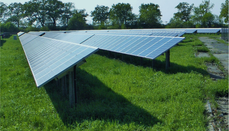Panele fotowoltaiczne są popularnym rodzajem odnawialnych źródeł energii (zdjęcie: Pixabay) Na trawie stoją panele fotowoltaiczne skierowane do słońca.