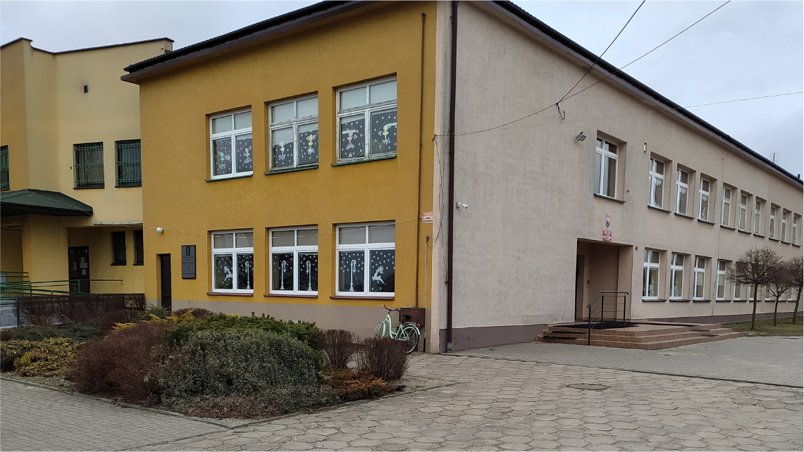 Szkoła podstawowa w Czajkowie o prostokątnej budowie. Jedna strona budynku jest pomarańczowa, a druga beżowa.