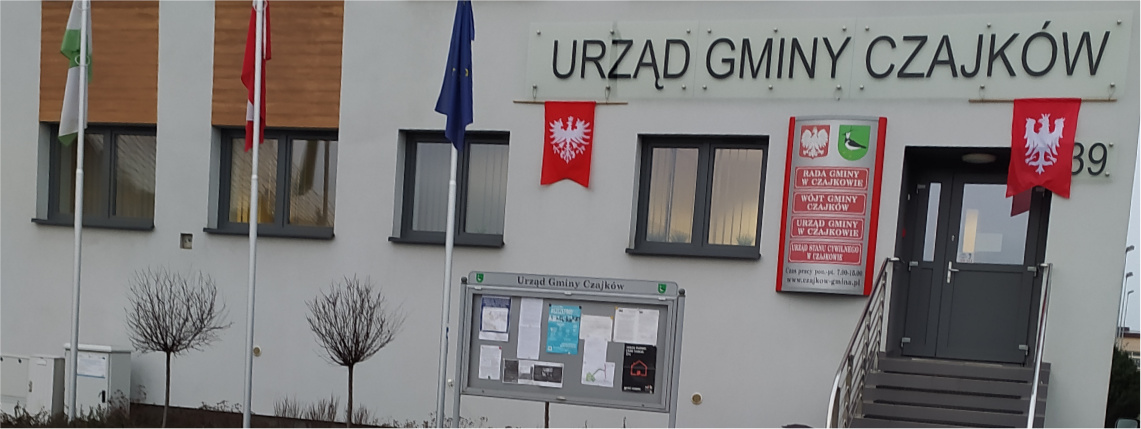 Gminę Czajków zamieszkuje aktywna społeczność lokalna Wejście do budynku Urzędu Gminy Czajków. Na białej elewacji wiszą czerwone, urzędowe tablice, a do drzwi prowadzą schody.