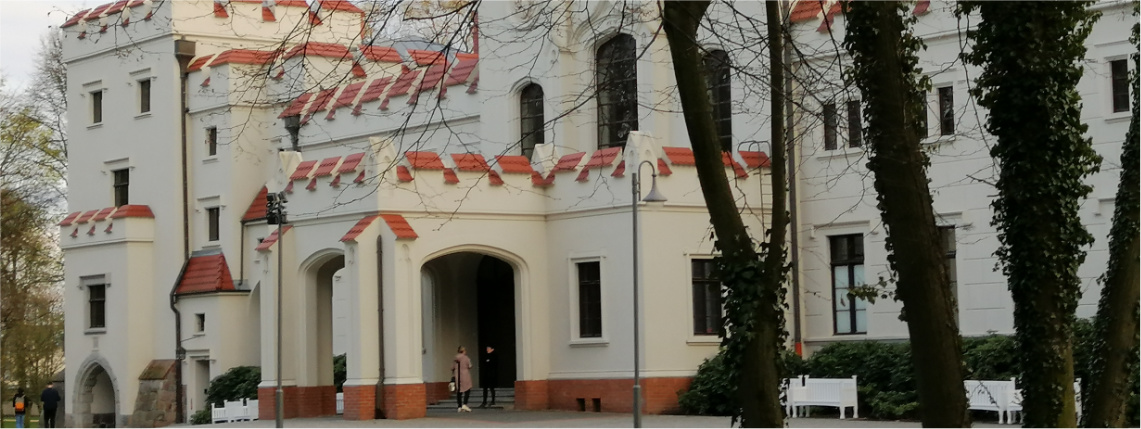 Front pałacu o białych ścianach i kwadratowej architekturze. 