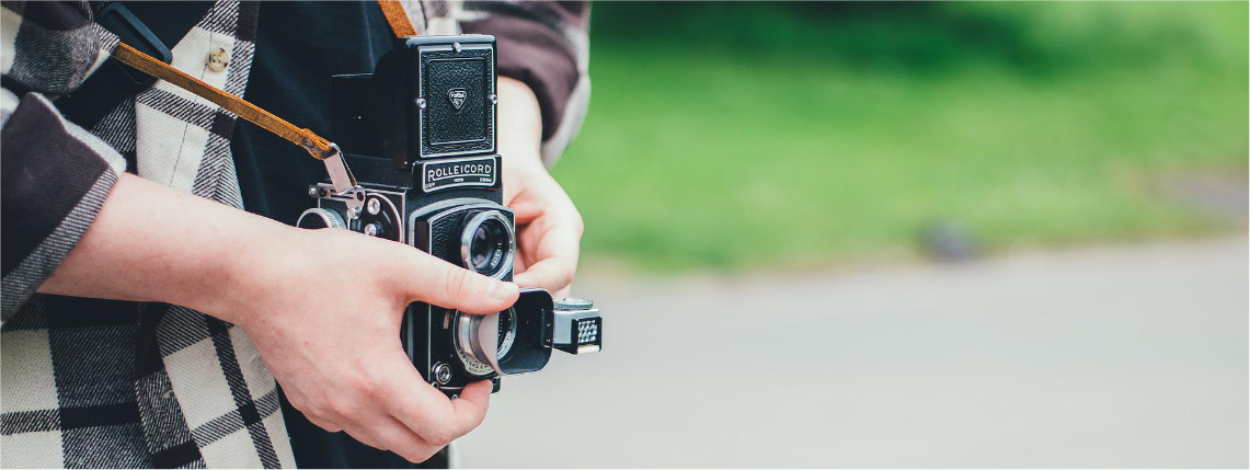 Konkurs fotograficzny „PROW w obiektywie – trzecia edycja” Zbliżenie na ręce osoby, która trzyma stary aparat.