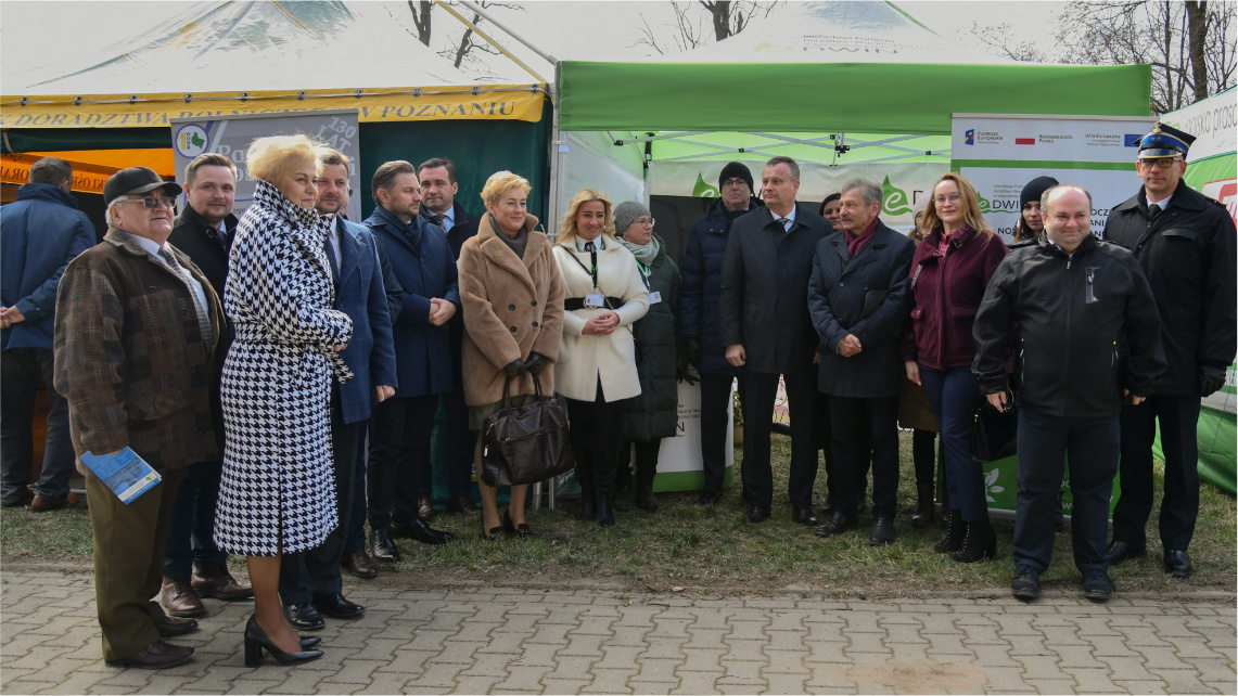 Przed namiotami stoi grupa ludzi, którzy pozują do zdjęcia.