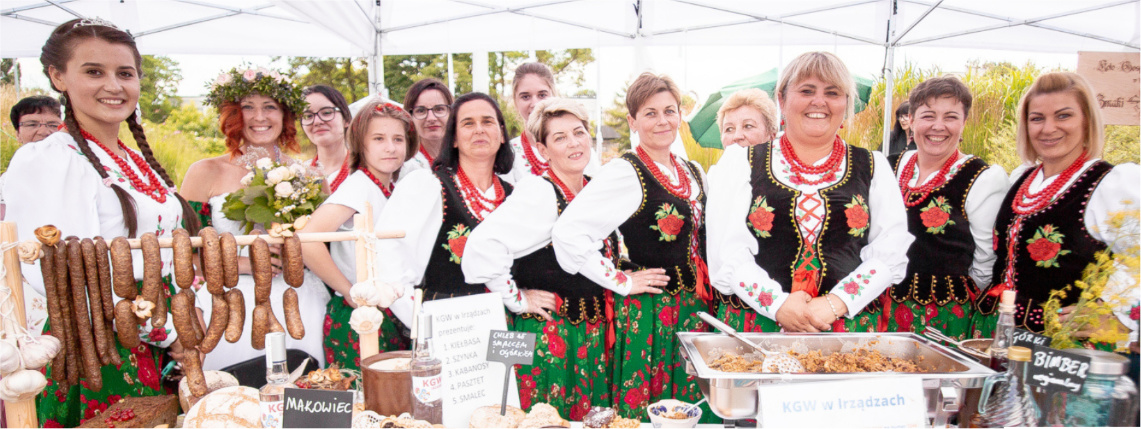 Grupa kobiet w strojach regionalnych uśmiecha się do zdjęcia. 