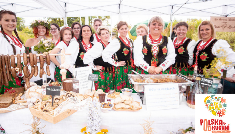 Grupa kobiet w strojach regionalnych uśmiecha się do zdjęcia. 