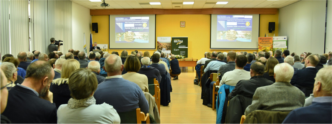 Sala pełna ludzi siedzących na krzesłach. To słuchacze forum pszczelarskiego.