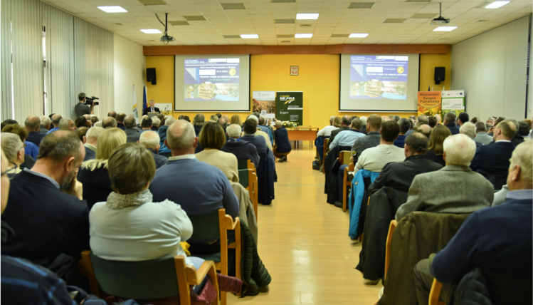 Sala pełna ludzi siedzących na krzesłach. To słuchacze forum pszczelarskiego.