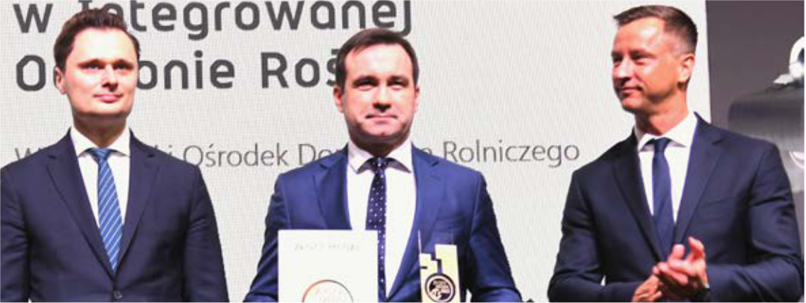 Lutowy numer Poradnika Gospodarskiego już dostępny! Trzech mężczyzn w garniturach. Mężczyzna pośrodku trzyma dwie statuetki.