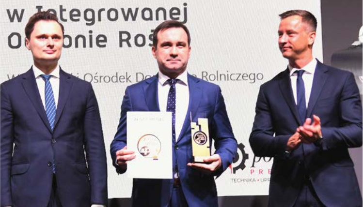 Lutowy numer Poradnika Gospodarskiego już dostępny! Trzech mężczyzn w garniturach. Mężczyzna pośrodku trzyma dwie statuetki.